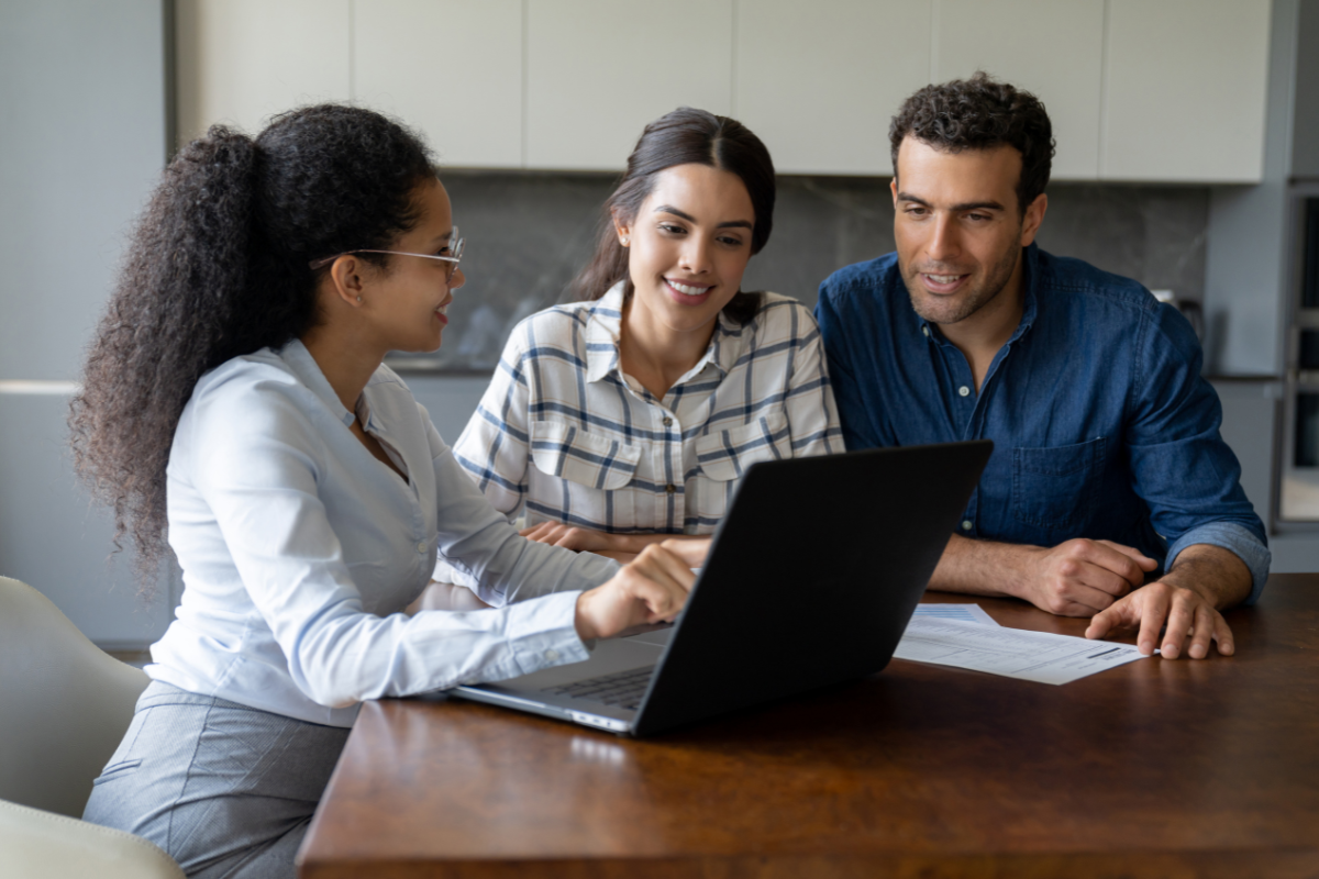 a group of people sitting at a desk looking at a laptop
